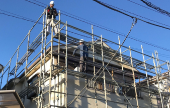 足場を組んだ建物で工事を行う業者の人達